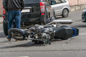 broken motorcycle closeup beside the car. an accident on the road in the city on a sunny day involving a motorcycle and a car.